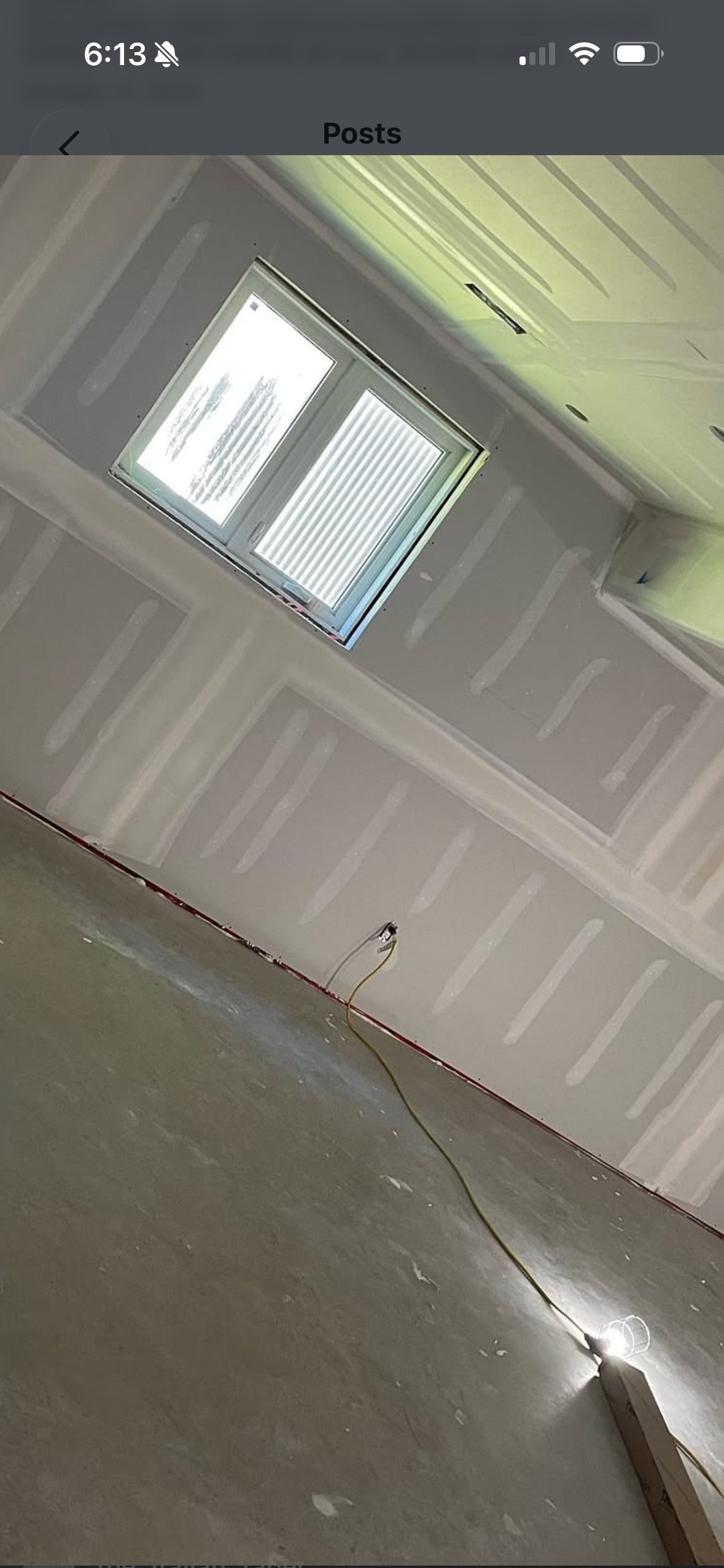 Interior ceiling view showing a rectangular skylight with vertical blinds, concrete floor, and electrical wire visible