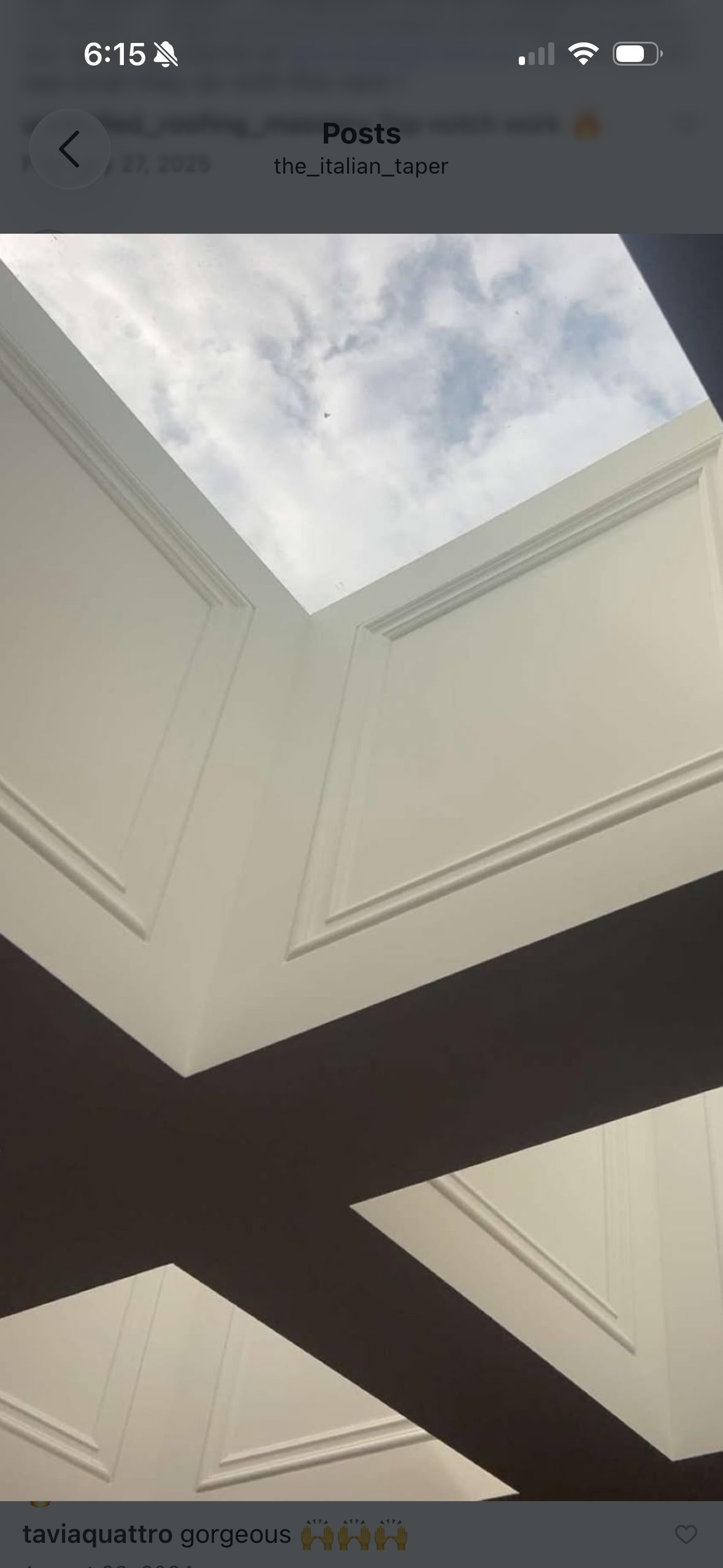 Interior view of a modern ceiling with geometric white panels and a skylight showing blue sky with clouds