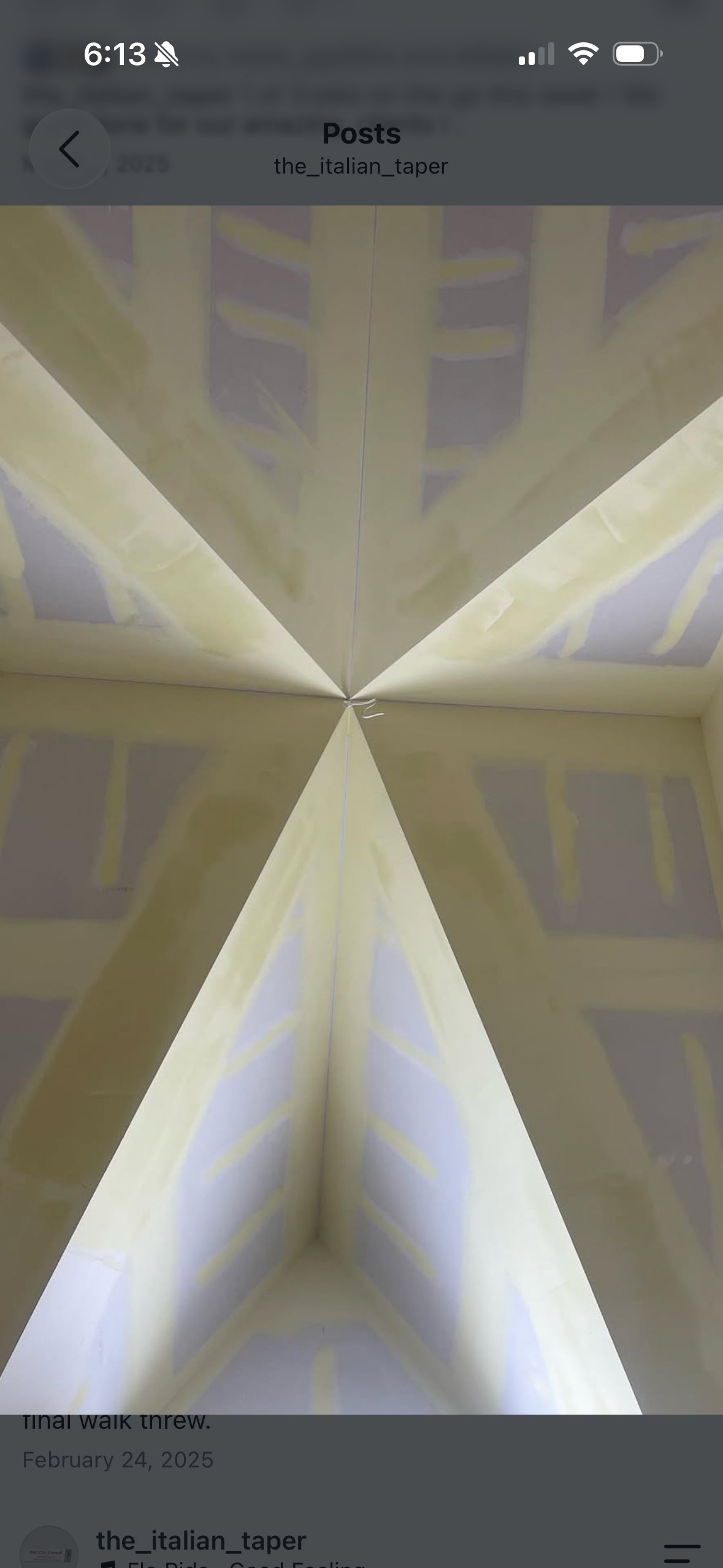 Symmetrical overhead view of white architectural beams converging to a point, with geometric shadows cast on ceiling and walls